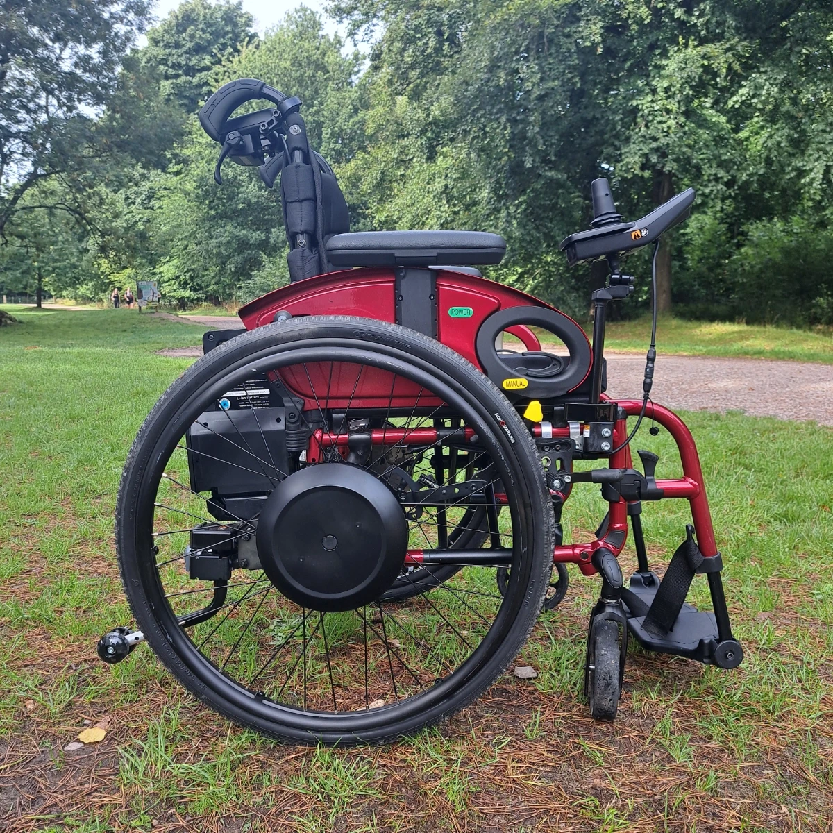 SD Motion Drive fitted to a red manual wheelchair in a park