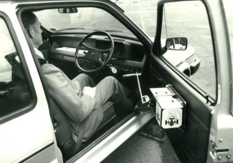 Driver using early Steering Developments hand controls in the 1980s